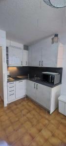 een keuken met witte kasten en een magnetron bij Résidence Héliovillage - Maisons & Villas pour 4 Personnes 944 - Naturiste in Cap d'Agde