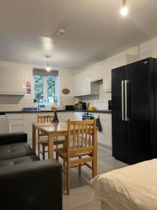 uma cozinha com uma mesa e um frigorífico preto em Lovely Double Rooms in Euston & Square em Londres