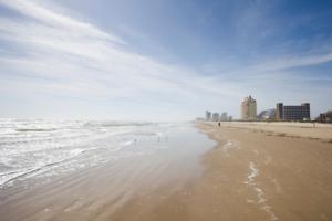 a beach with people walking in the water at Marlin Street C in South Padre Island