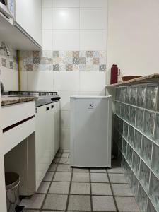 a white kitchen with a small refrigerator in it at Loft com vista da praia da Costa 612 in Vila Velha