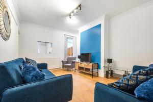 a living room with two blue couches and a television at The Mather Place in Blackpool