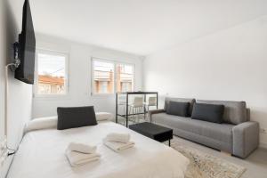 a white bedroom with a large bed and a couch at MADRIVER apartamentos reformados con parking gratuito in Madrid