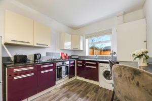 a kitchen with purple cabinets and a washer and dryer at The Mather Place in Blackpool