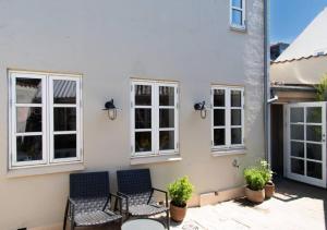 a patio with chairs and a building with windows at Nyrenoveret charmerende byhus in Fåborg