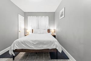 Vida Comfy Inn 3 bedroom Apartment 8 mins to downtown and ferry في نيو بدفورد: غرفة نوم بيضاء مع سرير أبيض مع مصباحين