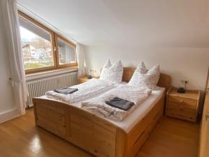 Schlafzimmer mit einem Holzbett mit weißer Bettwäsche und Kissen in der Unterkunft Ferienwohnung Partenkirchen in Garmisch-Partenkirchen
