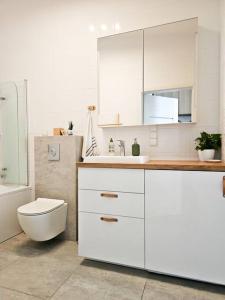 biała łazienka z toaletą i umywalką w obiekcie Oasis Oliwa w Gdańsku
