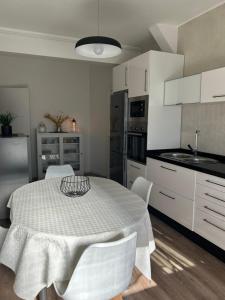 una cocina con mesa y sillas y una cocina con armarios blancos. en Acogedor Bajo en Meira, en Moaña