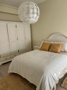 1 dormitorio con cama blanca y lámpara de araña en Acogedor Bajo en Meira, en Moaña