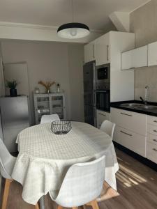 una cocina con mesa con sillas blancas y una cocina con en Acogedor Bajo en Meira, en Moaña