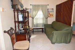 a living room with a green couch and a chair at Aileen Palm Cove Ja in Ocho Rios