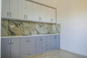 a kitchen with white cabinets and marble counter tops at Villa Mateo in Shkalle Stenojt