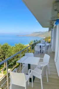 a balcony with white tables and chairs and the ocean at Villa Mateo in Shkalle Stenojt