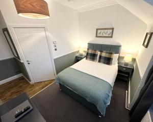 a small bedroom with a bed and two lamps at Ravenscraig Guest House in Aviemore