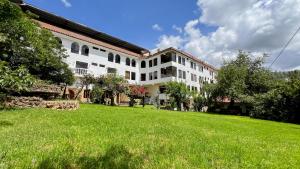 a large white building with a green field in front of it at La Mansion Casa Hotel in Andahuaylas