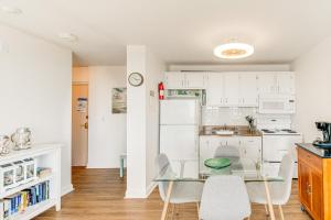 a kitchen with white cabinets and a glass table and chairs at Fort Myers Beach Studio with Balcony and Views! in Fort Myers Beach