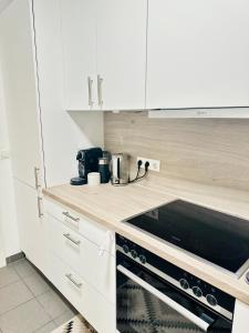 a kitchen with white cabinets and a black stove top oven at FMI Apartmets next to Frankfurt Airport in Frankfurt/Main