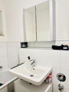 a white bathroom with a sink and a mirror at FMI Apartmets next to Frankfurt Airport in Frankfurt/Main