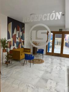 - un hall avec un canapé jaune et des fauteuils bleus dans l'établissement AljaLux Sevilla Bormujos, à Bormujos