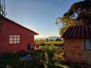 ein rotes Haus mit einem Feld im Hintergrund in der Unterkunft Mano de Oso Guasca in Guasca