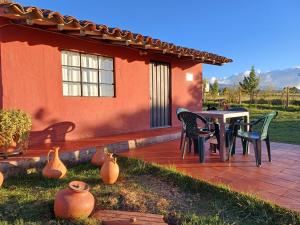 un patio con mesa y sillas frente a una casa en Mano de Oso Guasca son 3 hospedajes diversos en la ruralidad en Guasca