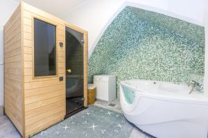 a bathroom with a tub and a green tile wall at Exclusive House in Old Town in Tallinn