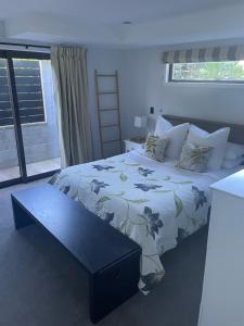 a bedroom with a bed and a bench in it at Luxury 2 Bdrm Apt w Private Pool located on Scarborough Hill, Sumner. Christchurch in Christchurch