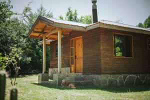 a small wooden cabin with a dog sitting in front of it at Cabañas Los Maquis in Pucón