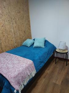 Schlafzimmer mit einem Bett mit blauer Bettwäsche und einem Tisch in der Unterkunft Minihouse castro chiloe in Castro