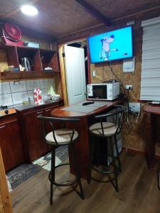 eine Küche mit einem Tisch mit Stühlen und einem TV in der Unterkunft Minihouse castro chiloe in Castro