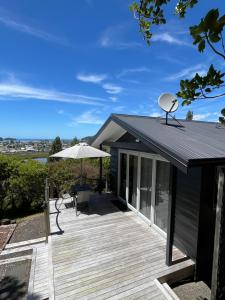a deck with an umbrella and a chair on a house at Mandhari - The View in Whangamata