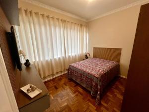 ein Schlafzimmer mit einem Bett und einem großen Fenster in der Unterkunft Apartamento Imperial no Centro de Petrópolis in Petrópolis