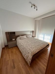 1 dormitorio con 1 cama y suelo de madera en APARTAMENTO MOAÑA - PLAYA A XUNQUEIRA, en Moaña