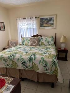 1 dormitorio con 1 cama con edredón verde y blanco en Aileen Palm Cove Ja en Ocho Rios
