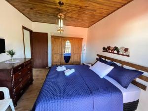 een slaapkamer met een blauw bed en een houten plafond bij Ap com Sacadas, 02 quartos e churrasqueira in Palhoça