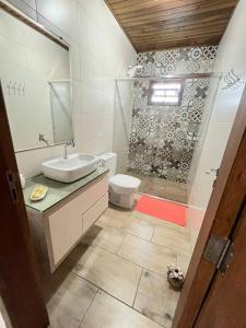 een badkamer met een wastafel, een toilet en een spiegel bij Ap com Sacadas, 02 quartos e churrasqueira in Palhoça