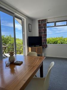 a dining room with a table and chairs and a television at Mandhari - The View in Whangamata