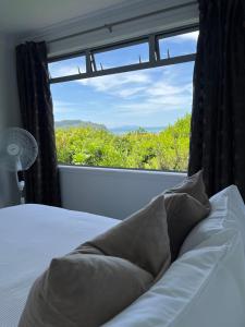 a bedroom with a bed and a large window at Mandhari - The View in Whangamata