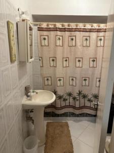a bathroom with a sink and a shower curtain with palm trees at Aileen Palm Cove Ja in Ocho Rios