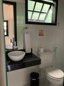ein Badezimmer mit einem Waschbecken, einem WC und einem Spiegel in der Unterkunft Baluarte Suites in Búzios