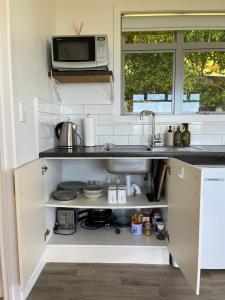 a kitchen with a sink and a microwave at Mandhari - The View in Whangamata