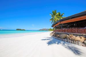 ein Gebäude an einem Strand mit einer Kokosnuss im Hintergrund in der Unterkunft Paradise Sun Hotel Seychelles in Baie Sainte Anne