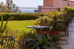 uma fila de mesas e cadeiras num jardim em Best Western Hotel Santa Caterina em Acireale