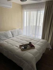 a white bed with a tray with two cups on it at CASA COMPLETA CON PATIO, ASADOR Y ESTACIONAMIENTO in Monterrey