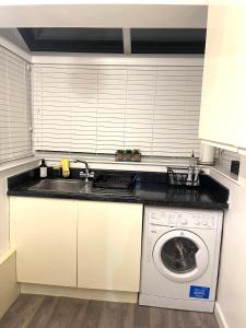 eine Küche mit einer Spüle und einer Waschmaschine in der Unterkunft Cozy Apartment in Birchwood in Risley