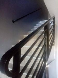a staircase with a black rail and a metal railing at Cozy 2 storey fully furnished house. in Davao City