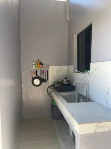 a white kitchen with a sink and a mirror at Cozy 2 storey fully furnished house. in Davao City