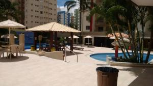 einen Pool mit Sonnenschirmen und Stühlen sowie einen Pool in der Unterkunft Privê das Thermas 1 / Apto 2 Qtos in Caldas Novas