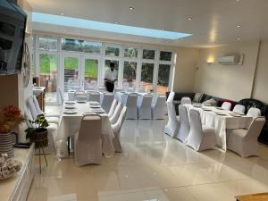 un restaurant avec des tables blanches, des chaises blanches et un homme dans l'établissement Rose Garden House, à Luton