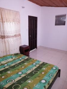 a bedroom with a bed with a green blanket on it at Casa de relajación low cost in La Dorada